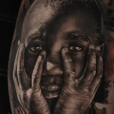 Realistic tattoo of a child with hands on face