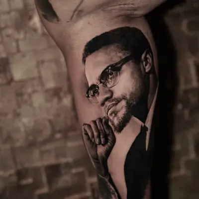 Black and grey realistic portrait tattoo of a man with glasses and beard.