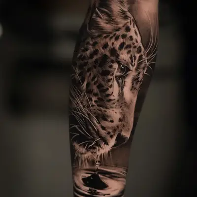 Realistic leopard tattoo with water droplet reflection on forearm.