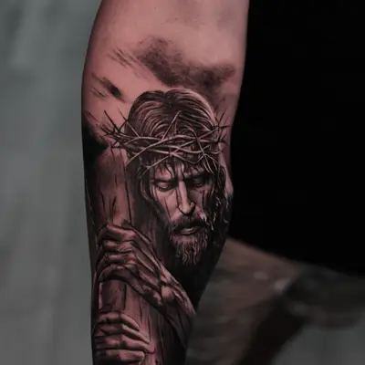 Black and grey tattoo of Jesus with crown of thorns on forearm.