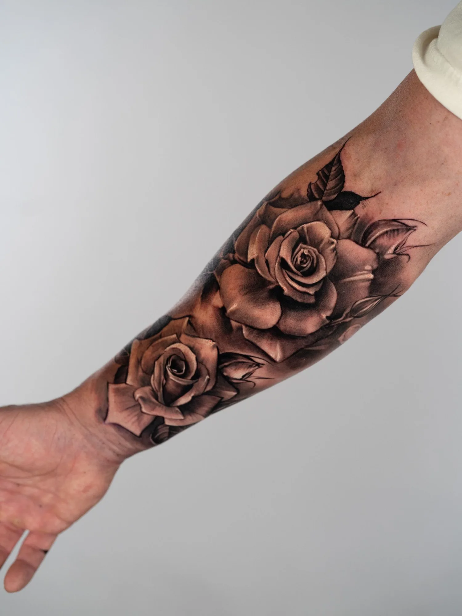Black and grey realism rose tattoo on a forearm. 