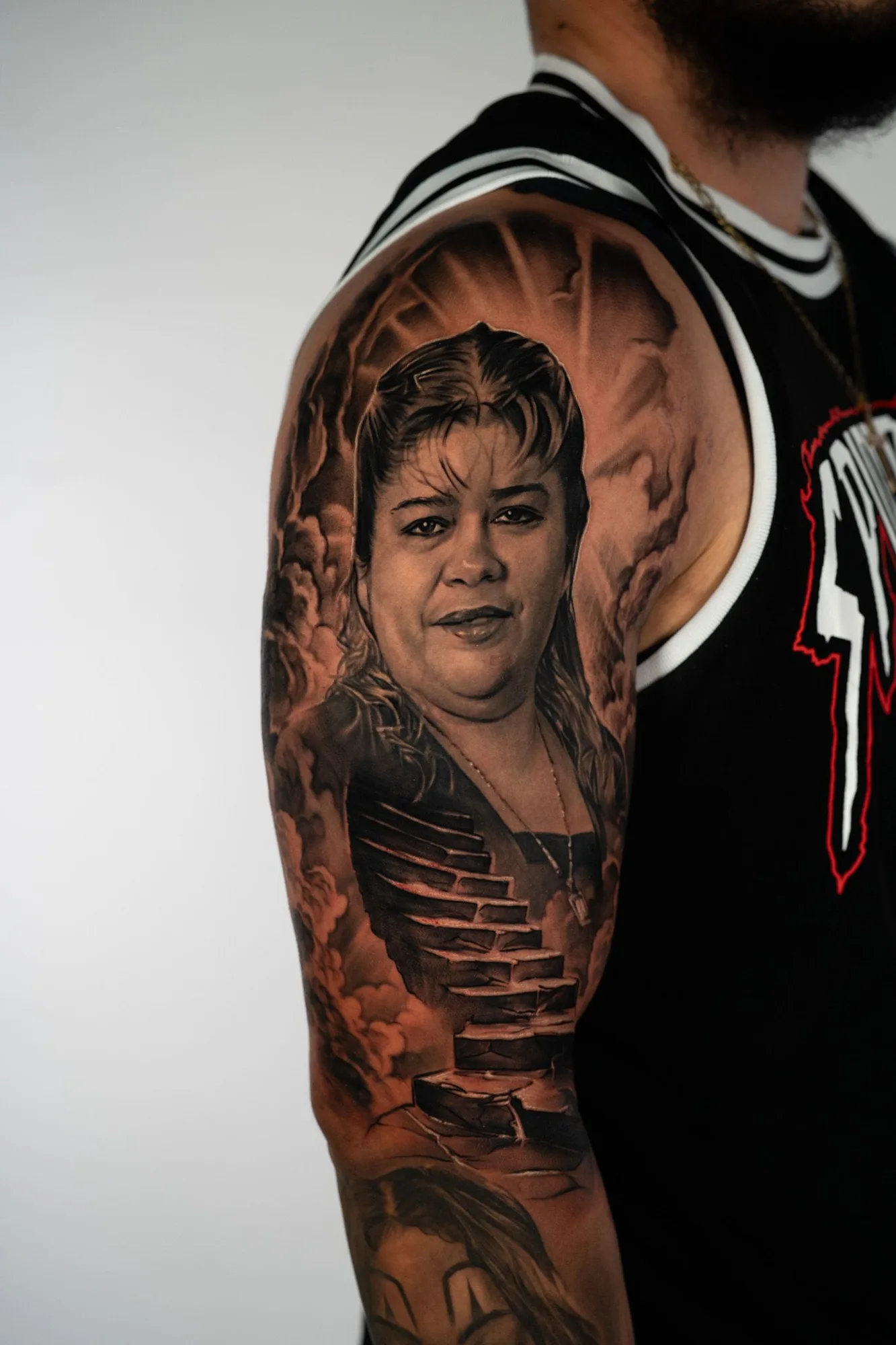 A detailed black and grey tattoo of a woman's portrait with surreal elements.