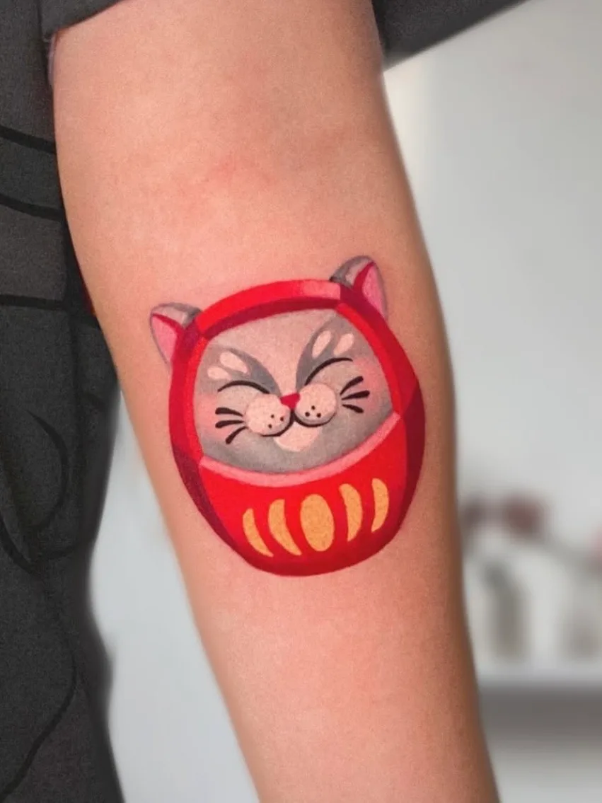 Tattoo of a smiling cat in a red costume on an arm