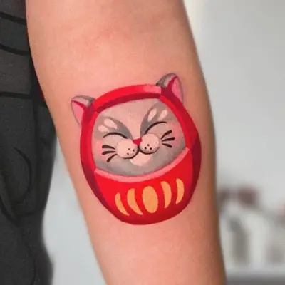 Tattoo of a smiling cat in a red costume on an arm