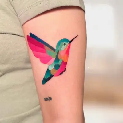Colorful geometric hummingbird tattoo on upper arm.