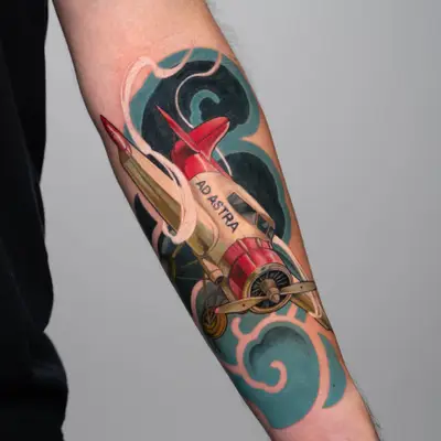 Tattoo of red airplane with 'Ad Astra' banner on arm