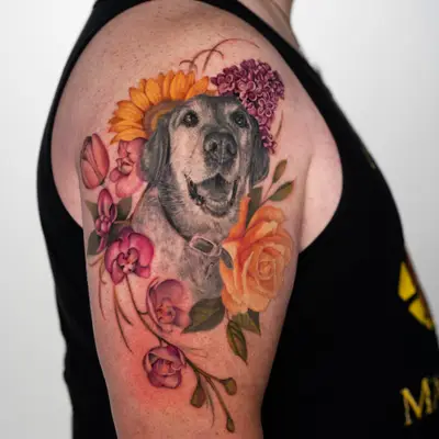 Tattoo of a dog's portrait surrounded by colorful flowers on an arm.