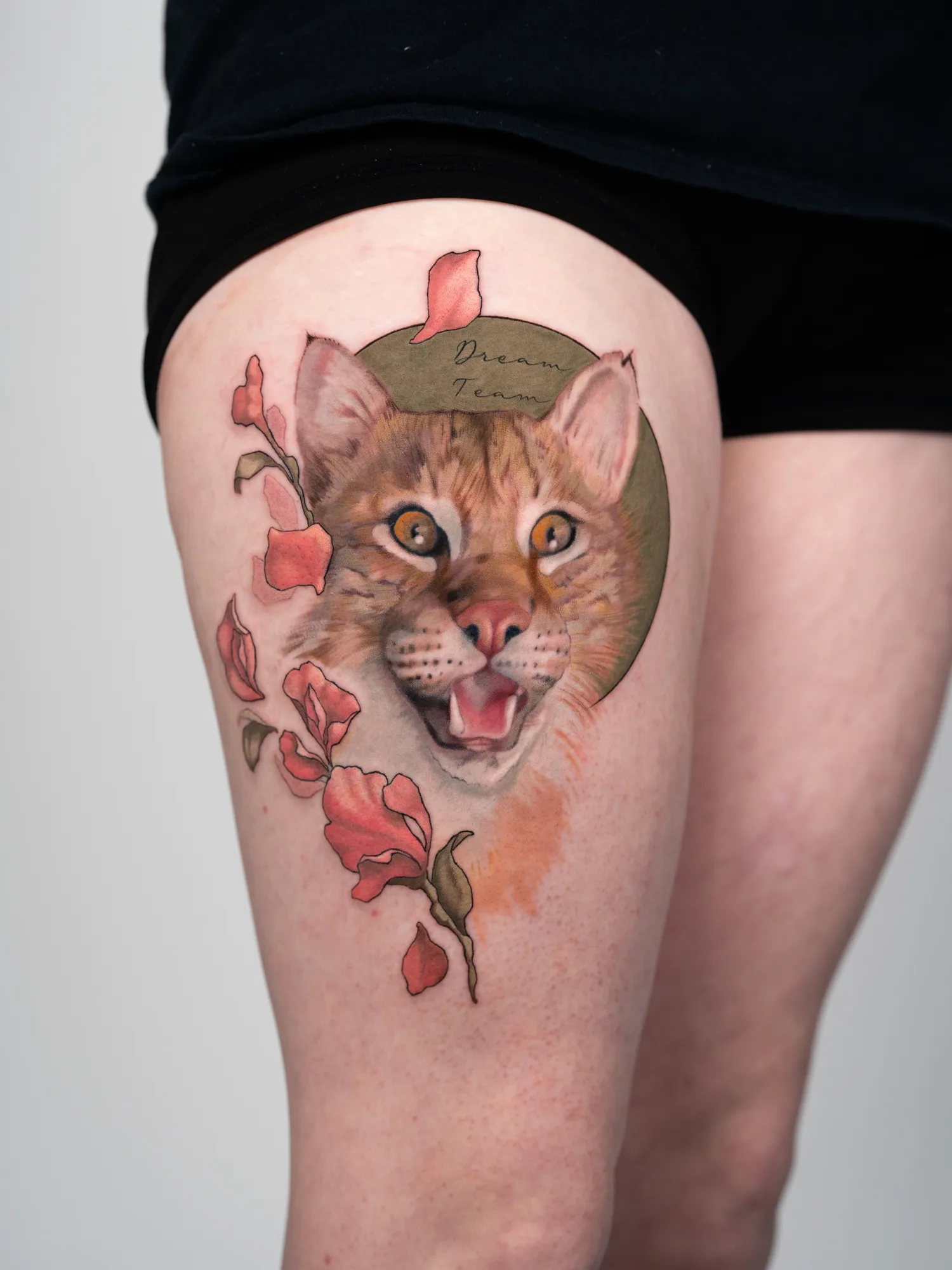 Realistic cat face tattoo with flowers on thigh