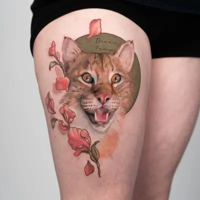 Realistic cat face tattoo with flowers on thigh