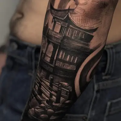 Black and grey tattoo of a traditional Asian temple on the arm.
