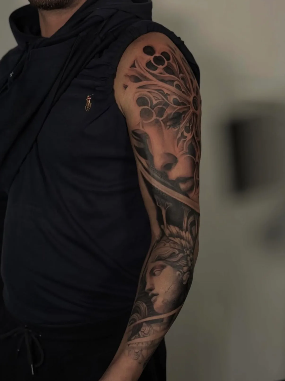 Realistic sleeve tattoo with abstract and portrait elements on arm.