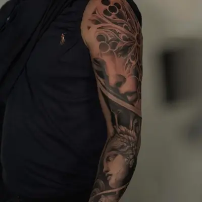 Realistic sleeve tattoo with abstract and portrait elements on arm.
