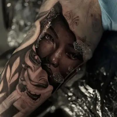 Tattoo of a realistic woman's face and stylized mask.
