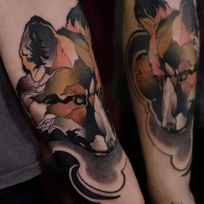 Two color neo-traditional fox heads on two forearms, side by side, in rust, ochre, moss green and black: one finished with a sweeping black wave at the wrist, the other inside a thin outlined frame.