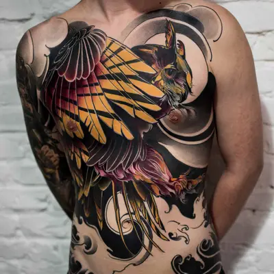 Tattoo of a stylized owl with bold colors on a person's chest.