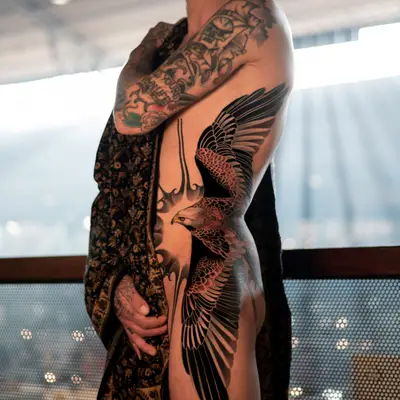 Tattoo of a bird in flight with detailed wings on a person's torso.