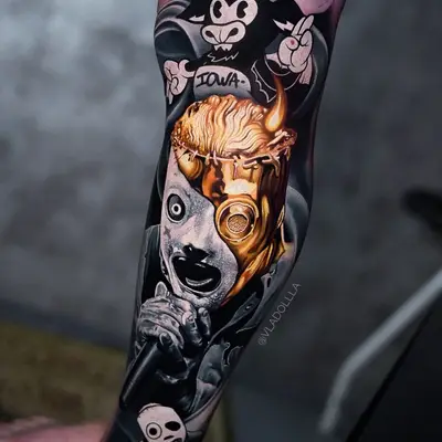 Black and grey and gold Slipknot leg sleeve on the lower leg: a cartoon goat holding an Iowa sign just below the knee, Corey Taylor in his mask with gold hair and a gold eyepiece singing into a microphone down the shin, and a small masked cartoon figure at the ankle.