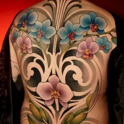 Back tattoo with vibrant orchids and black ornamental swirls.