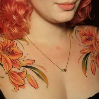 Two orange lily tattoos on woman's shoulders.