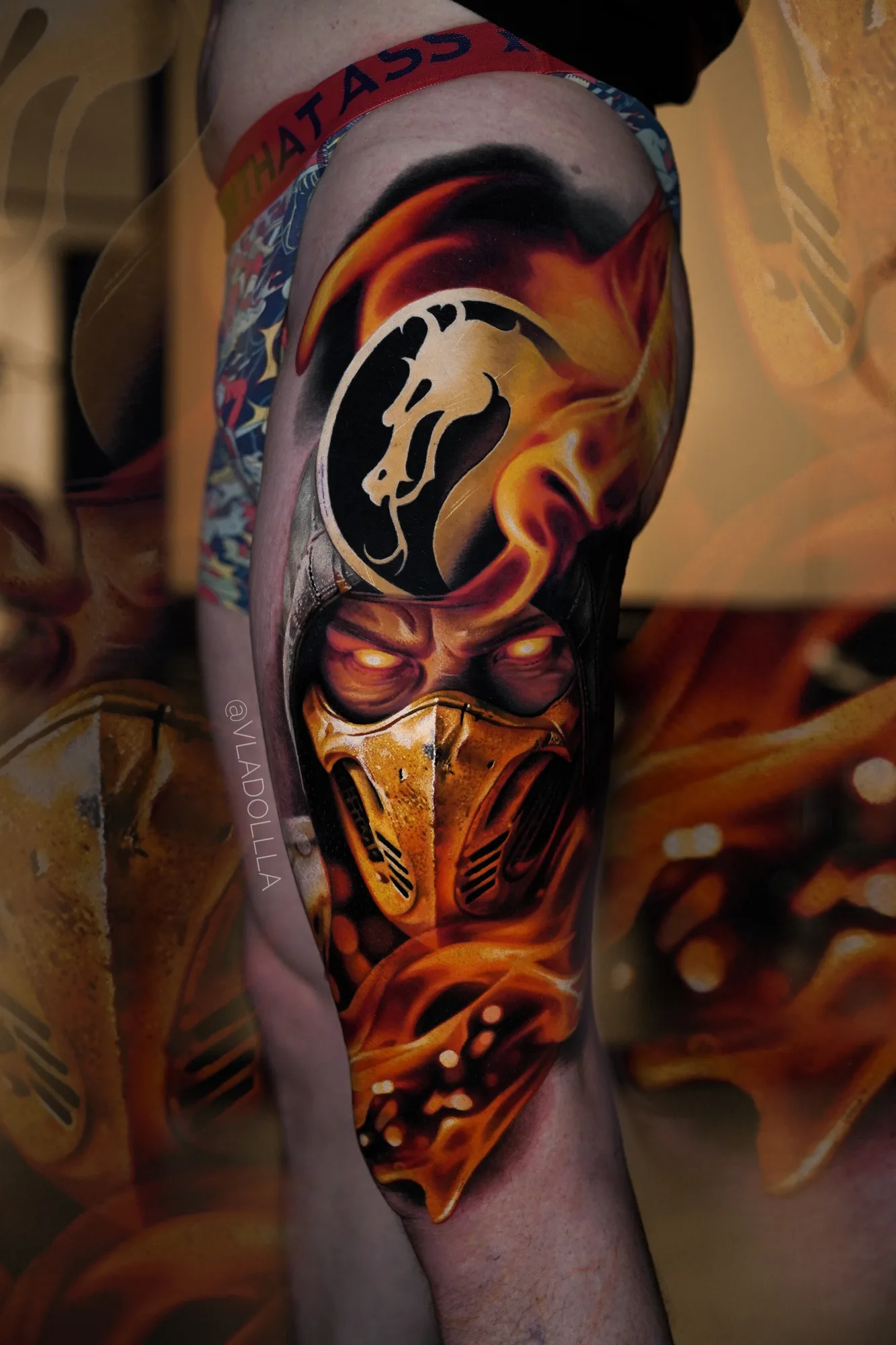 Color realism thigh piece of Scorpion from Mortal Kombat, gold mask in flames under the dragon crest.