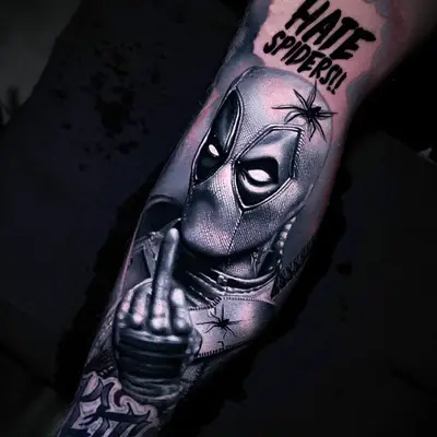Black and grey tattoo of Deadpool with comic text and spider.