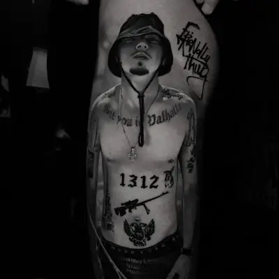 Black and grey realism tattoo on the thigh: a full-length portrait of a shirtless young man in a bucket hat with tattoos across his chest and stomach, and graffiti lettering reading "Friendly Thug" beside him.