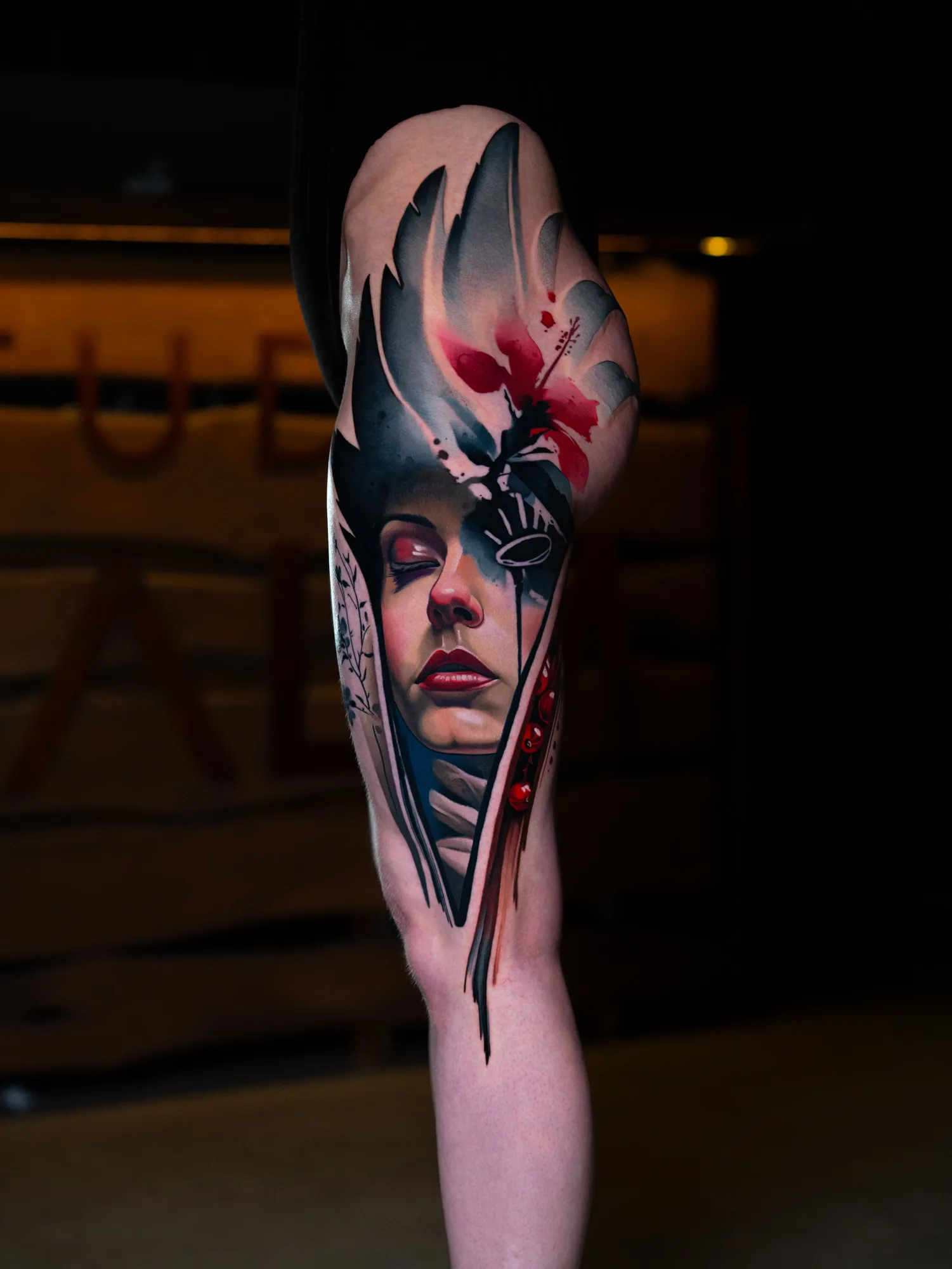 Abstract color realism tattoo of a woman's face on a thigh