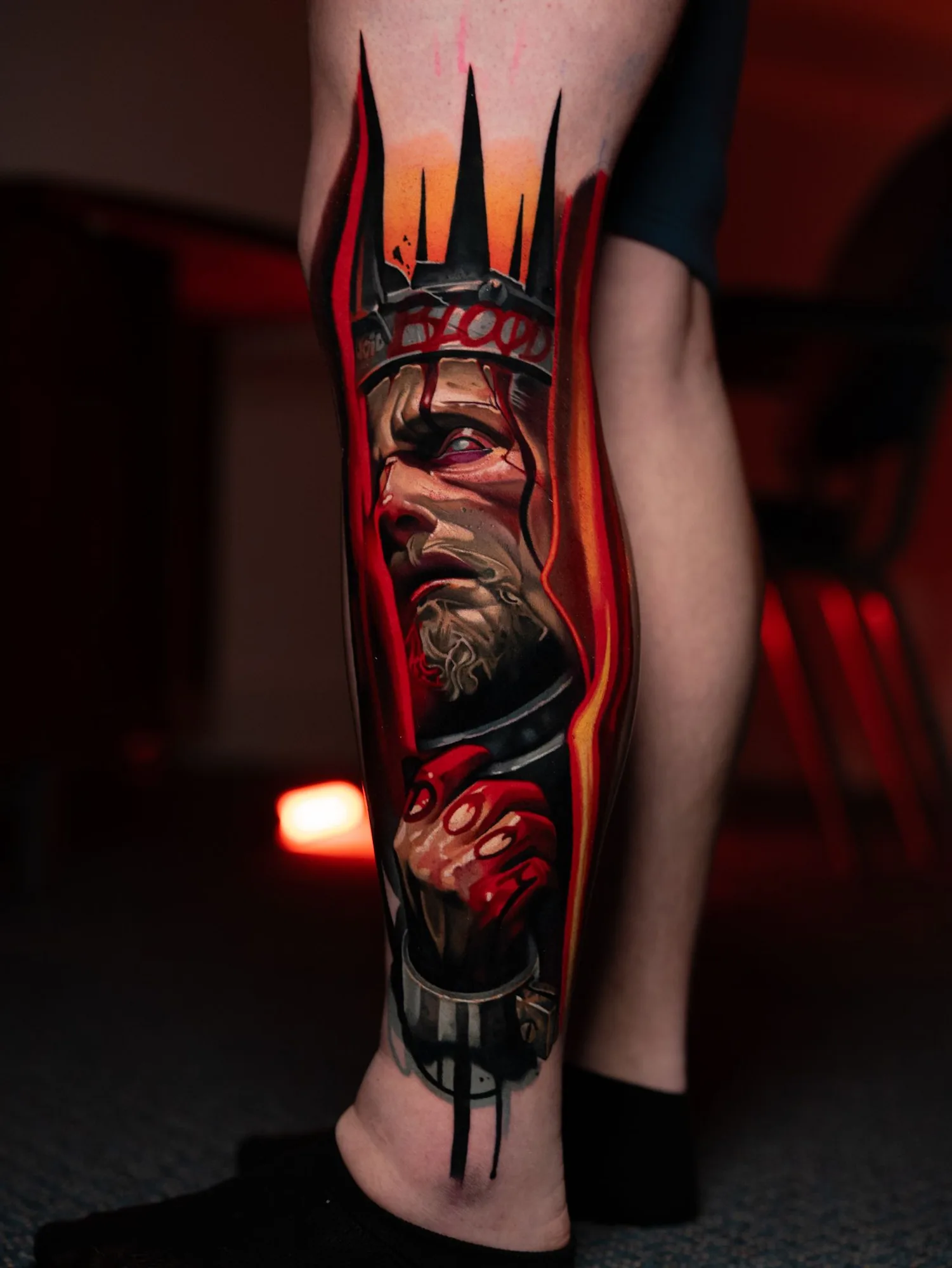 Color realism tattoo of a crowned king with bloodied hands on a lower leg