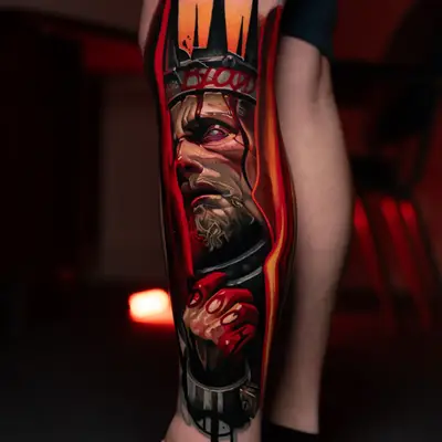 Color realism tattoo of a crowned king with bloodied hands on a lower leg