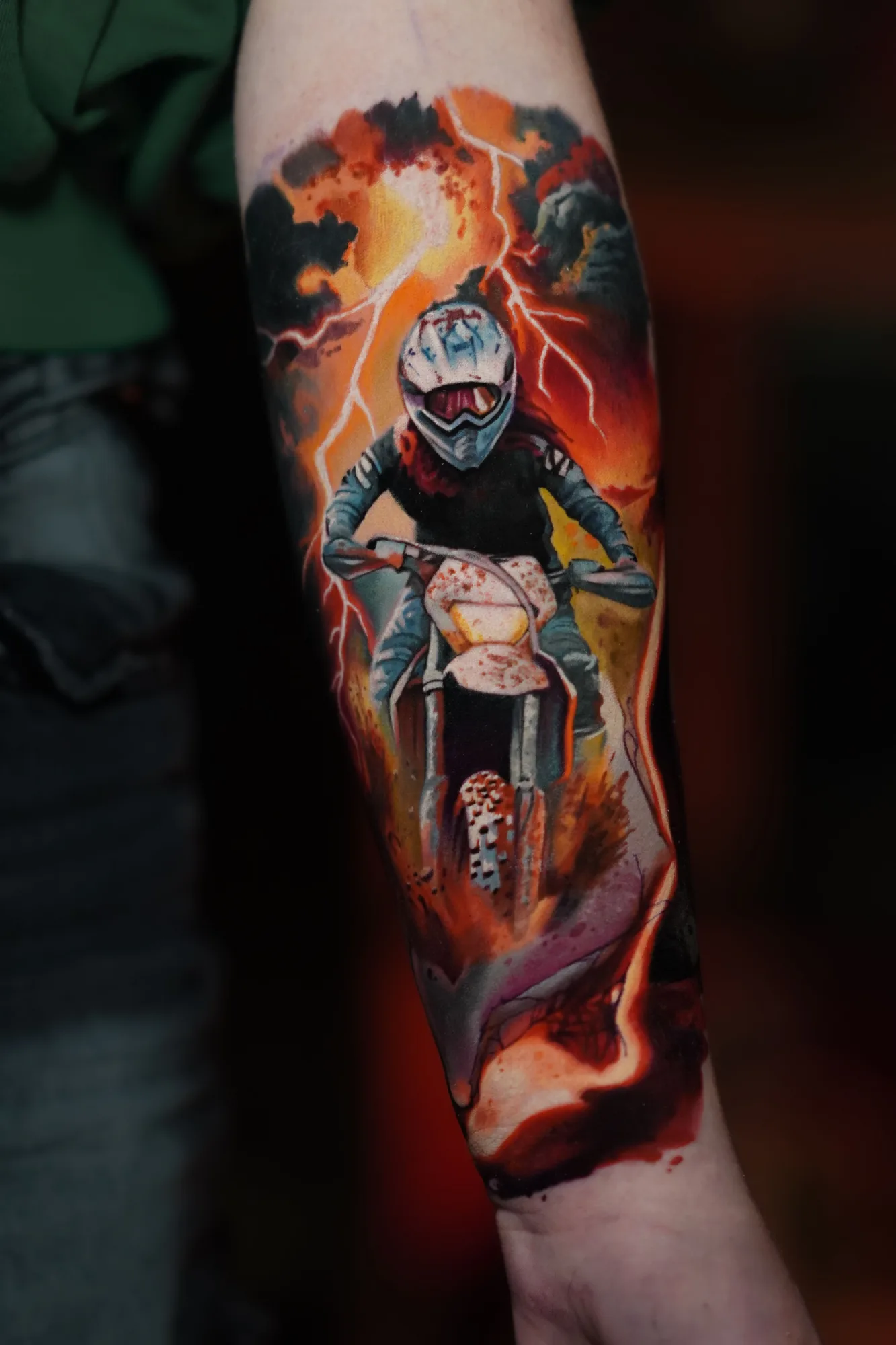 Color realism tattoo of a motocross rider coming out of fire on a forearm
