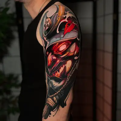 Color realism tattoo of a red Japanese demon mask on a shoulder and upper arm