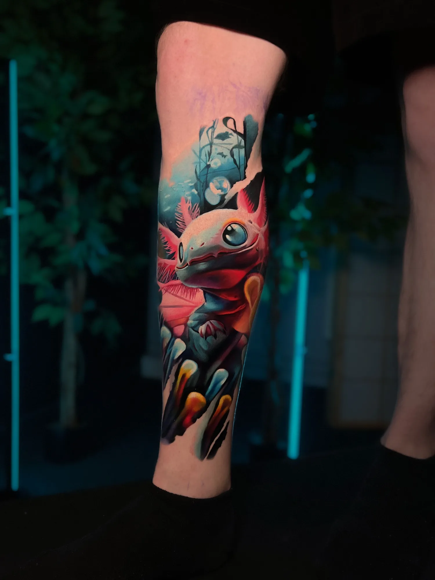 Color realism tattoo of a pink axolotl on a lower leg