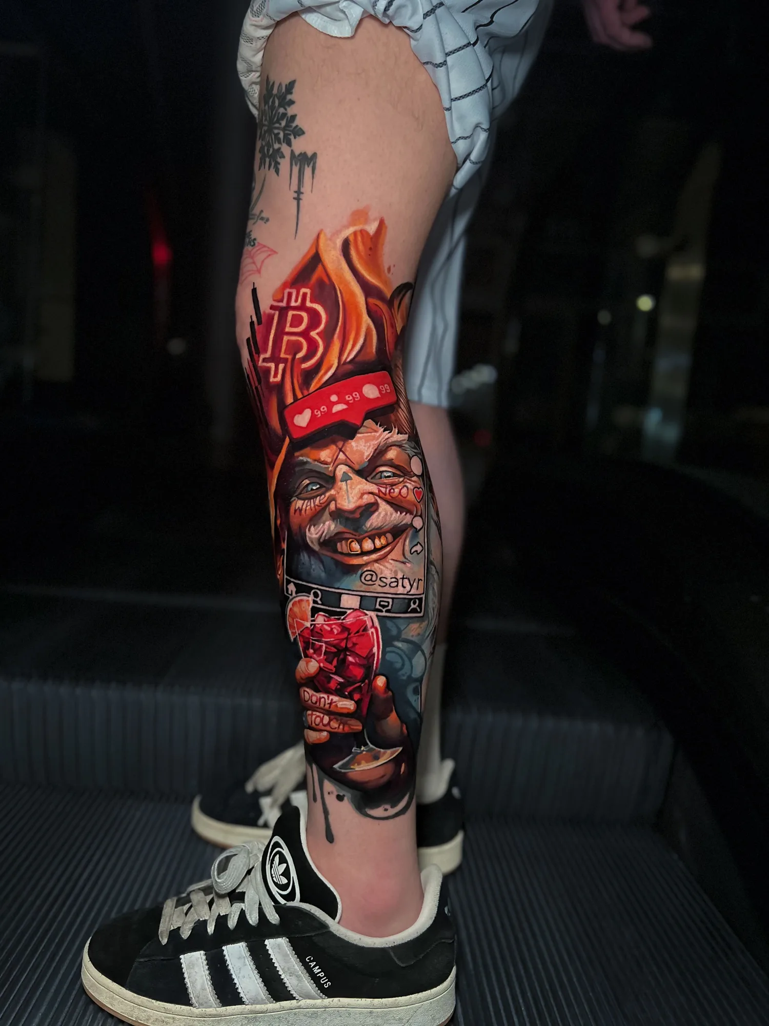 Color realism tattoo of a grinning satyr in a flaming bandana on a lower leg
