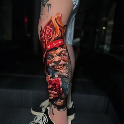 Color realism tattoo of a grinning satyr in a flaming bandana on a lower leg