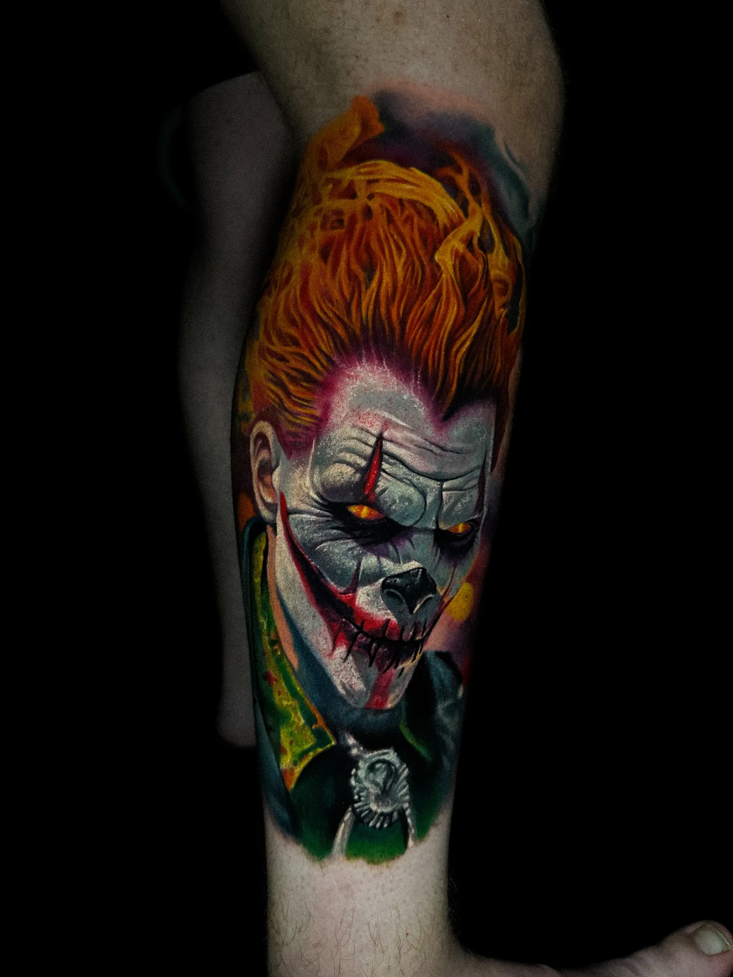 Tattoo of face with fiery hair and menacing features on arm.