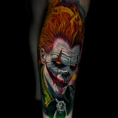 Tattoo of face with fiery hair and menacing features on arm.