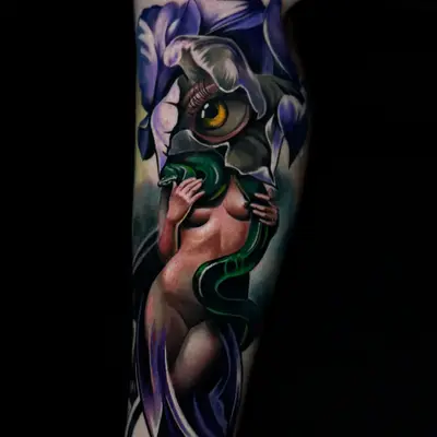 Color realism tattoo on the calf of purple irises with a figure, a green serpent and a large eye