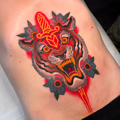 Tattoo of a tiger in an American traditional style with a dagger in neon through its head.