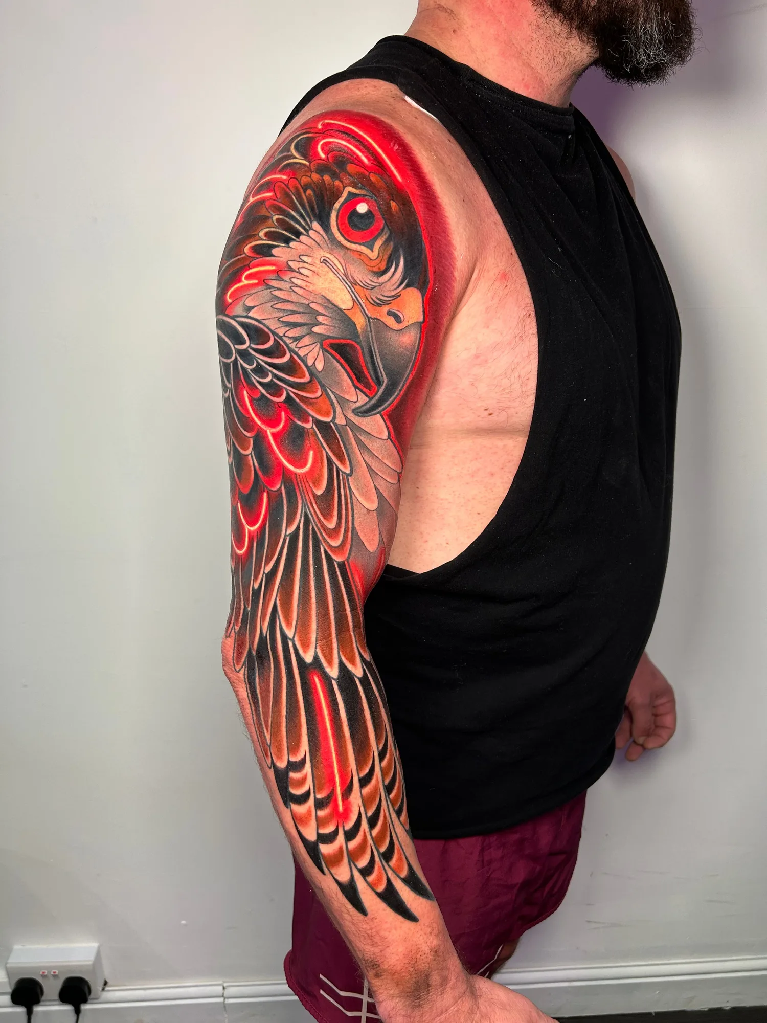 Vibrant arm tattoo of a bird with decorative wings and bold colors.