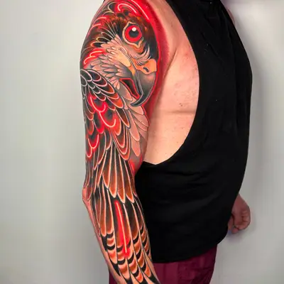 Vibrant arm tattoo of a bird with decorative wings and bold colors.
