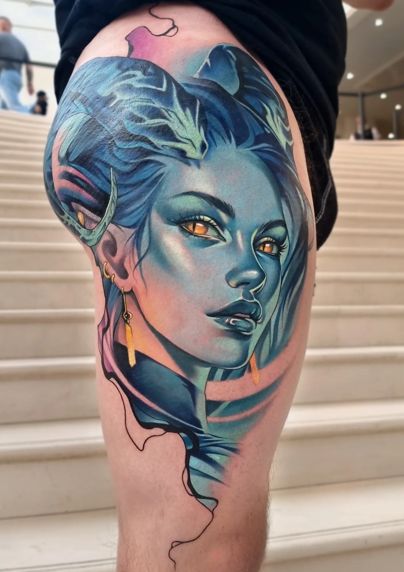 Colorful portrait tattoo of a woman with blue hair and striking horns and elvish features on the thigh.