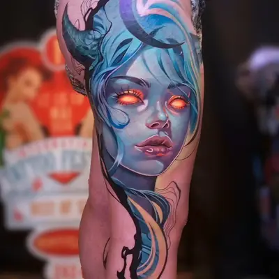 Colorful tattoo of a woman's face with blue hair and orange glowing eyes on the thigh.