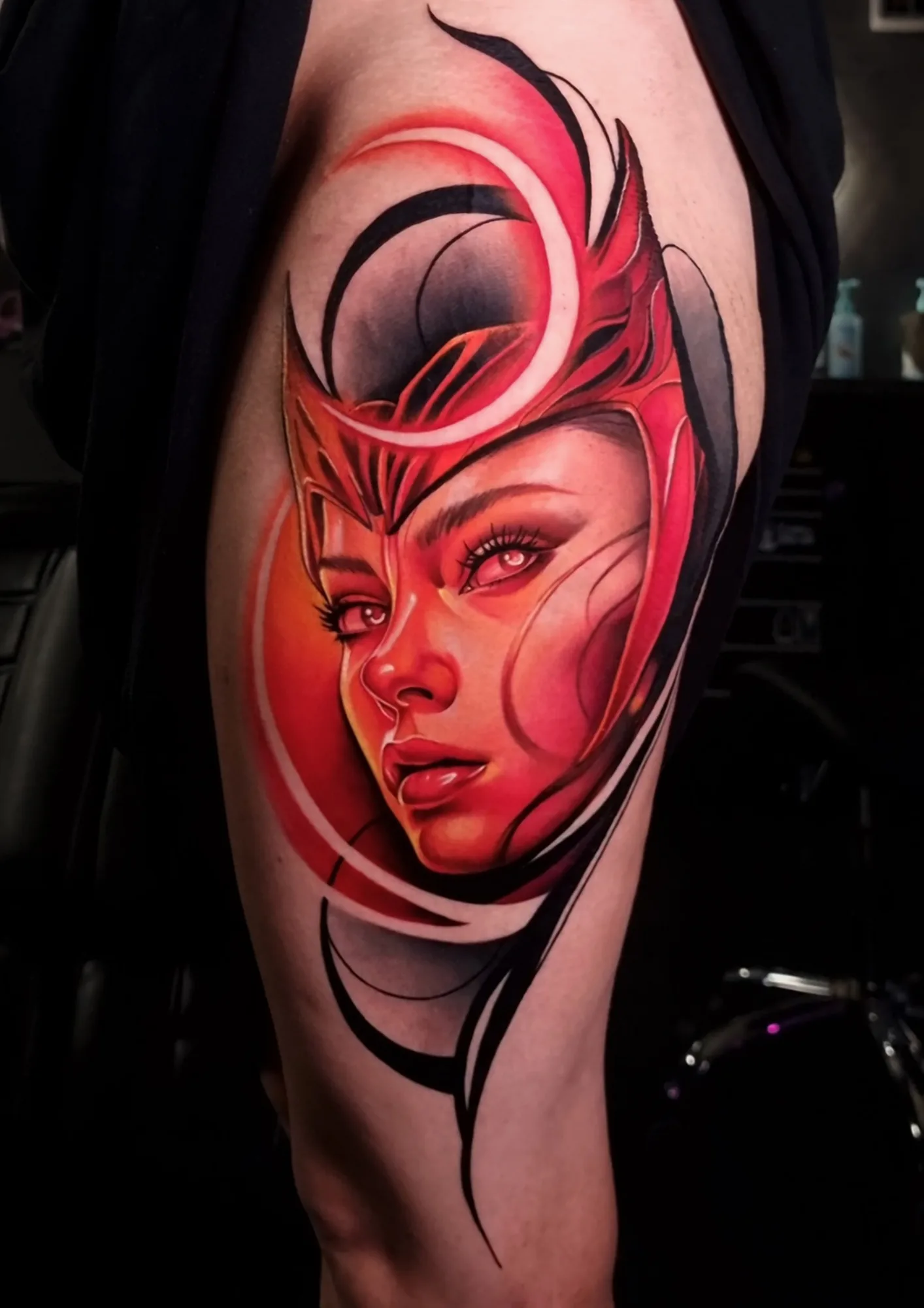 Tattoo of Scarlet Witch rendered in a monochromatic red portrait with abstract elements on the thigh.