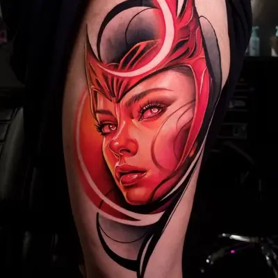 Tattoo of Scarlet Witch rendered in a monochromatic red portrait with abstract elements on the thigh. 