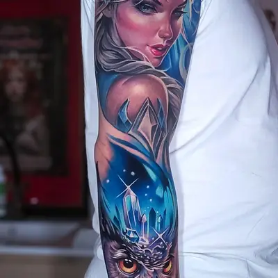 Full sleeve tattoo with a portrait of queen with gemstones and an owl with an icy blue theme.