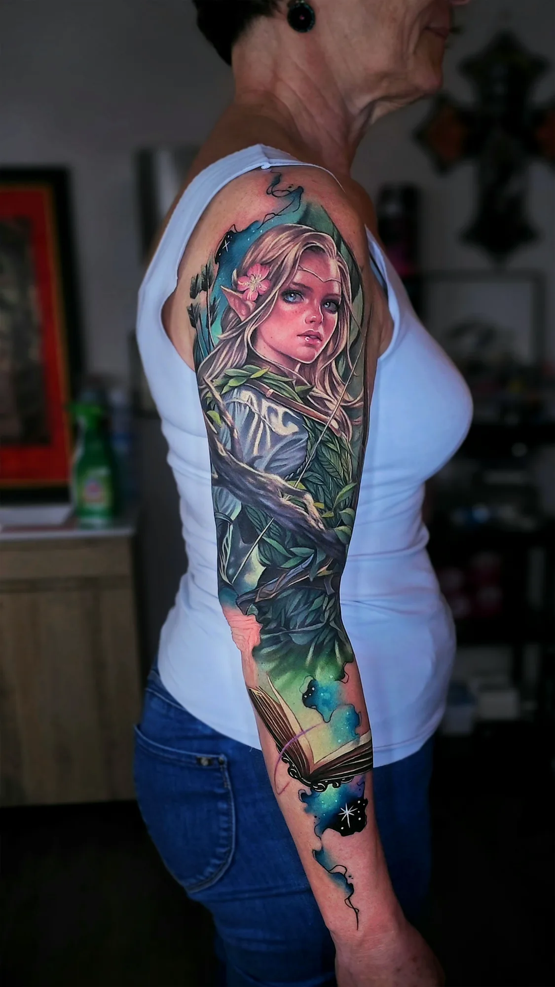 Full sleeve tattoo of an elvish archer with a storybook in full color.
