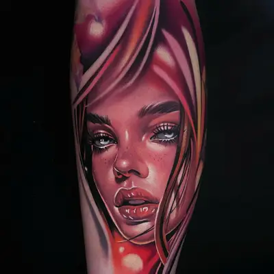 Color neorealist portrait of a woman framed by flowing red and pink hair with pale blue eyes and freckles, tattooed on the calf.