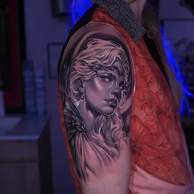Black and grey opaque neorealist portrait of the goddess Artemis with a thorned circlet, pale eyes and flowing hair, on the upper arm and shoulder, in progress.