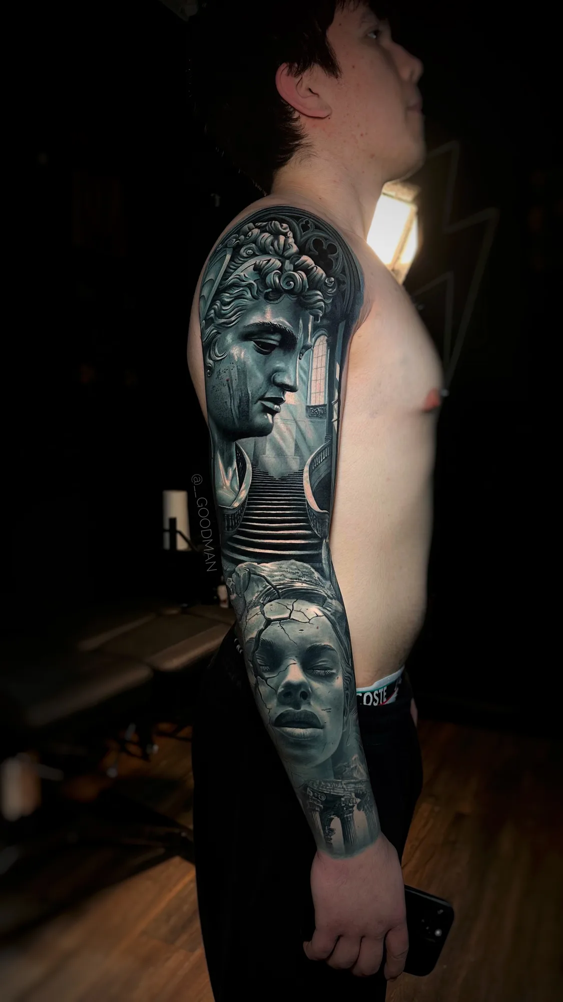 Black and grey full sleeve tattoo featuring statues and architectural elements.