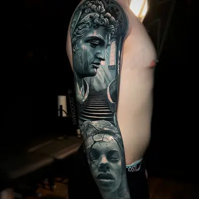 Black and grey full sleeve tattoo featuring statues and architectural elements.